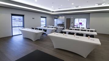 A conference room with multiple tables, chairs, and a large screen.