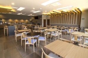 A modern restaurant with multiple seating areas, including round tables and booths, and a visible bar area with a counter and seating. - City Express Plus by Marriott Ciudad de México Mundo E (Tlalnepantla de Baz)