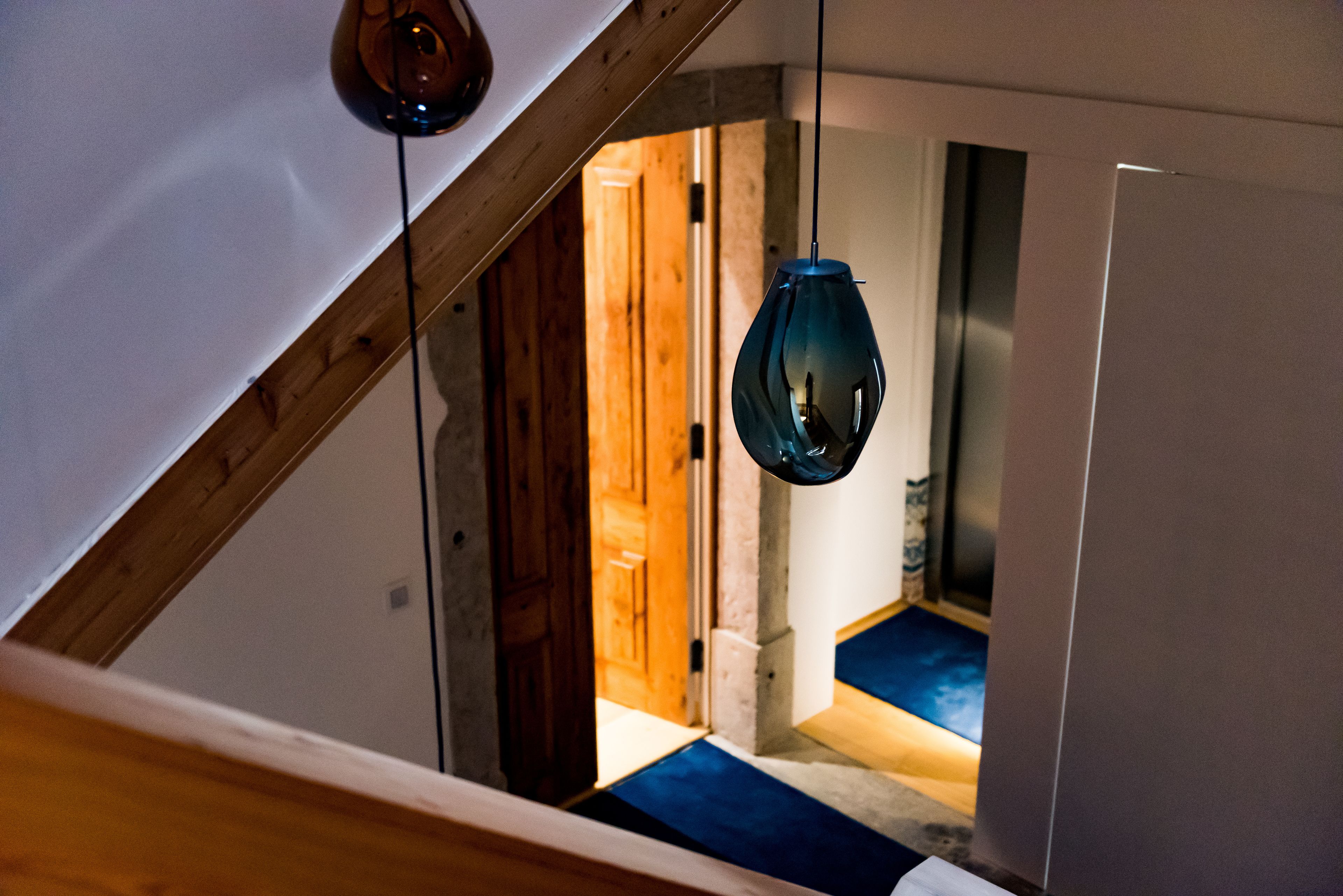 Una escalera con barandilla de madera y un rellano cubierto de moqueta azul.