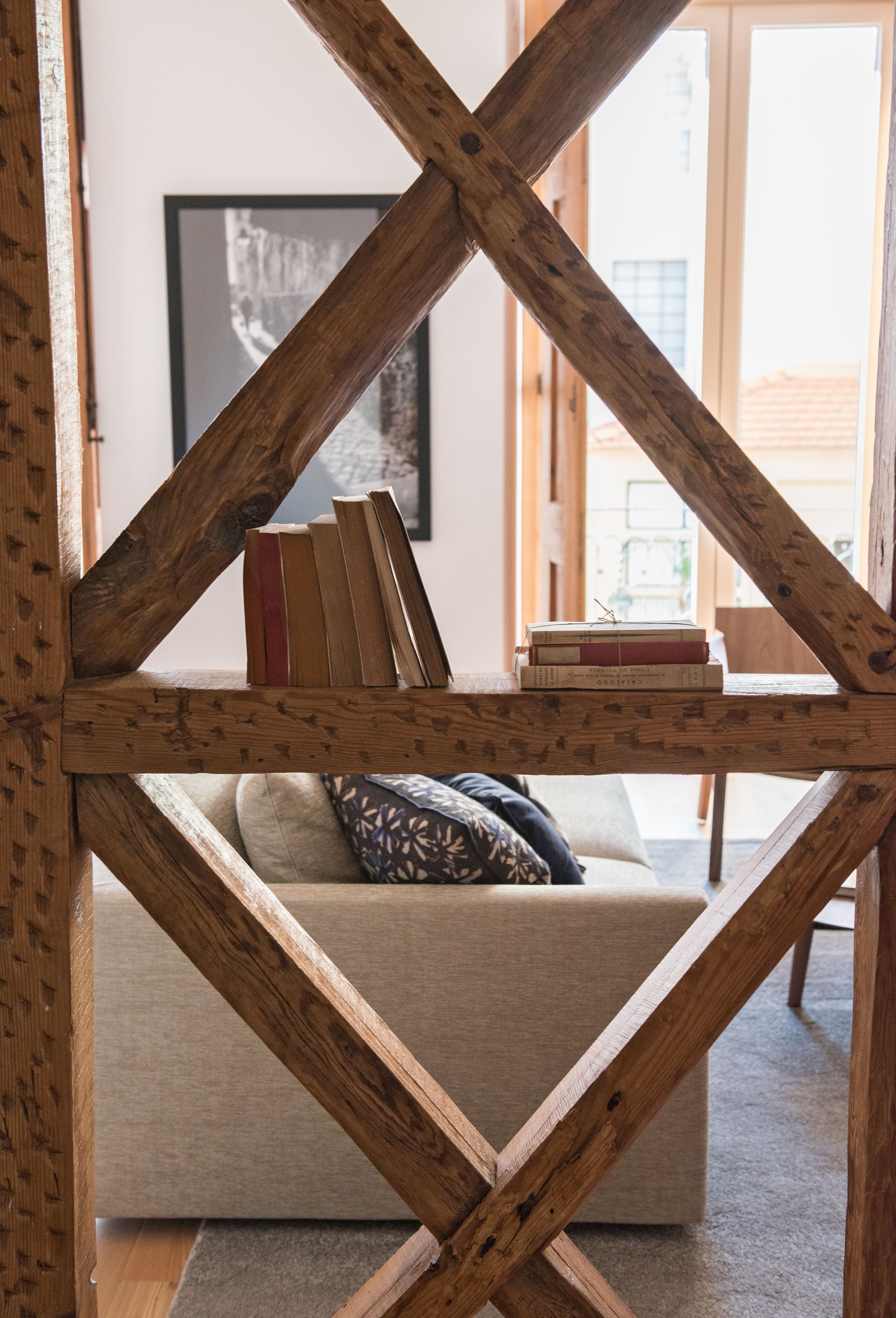 A wooden bookshelf with books and a couch in the background.