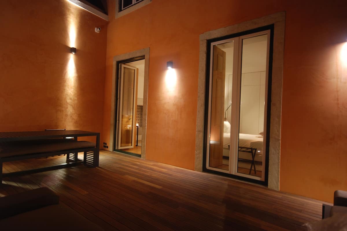 A room with a wooden bench, a bed, and a large mirror.