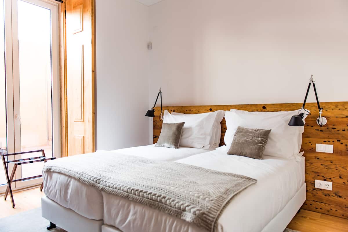 A double bed with a wooden headboard, two bedside lamps, and a neutral color scheme.