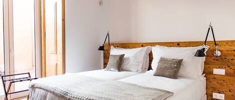 A double bed with a wooden headboard, two bedside lamps, and a neutral color scheme.