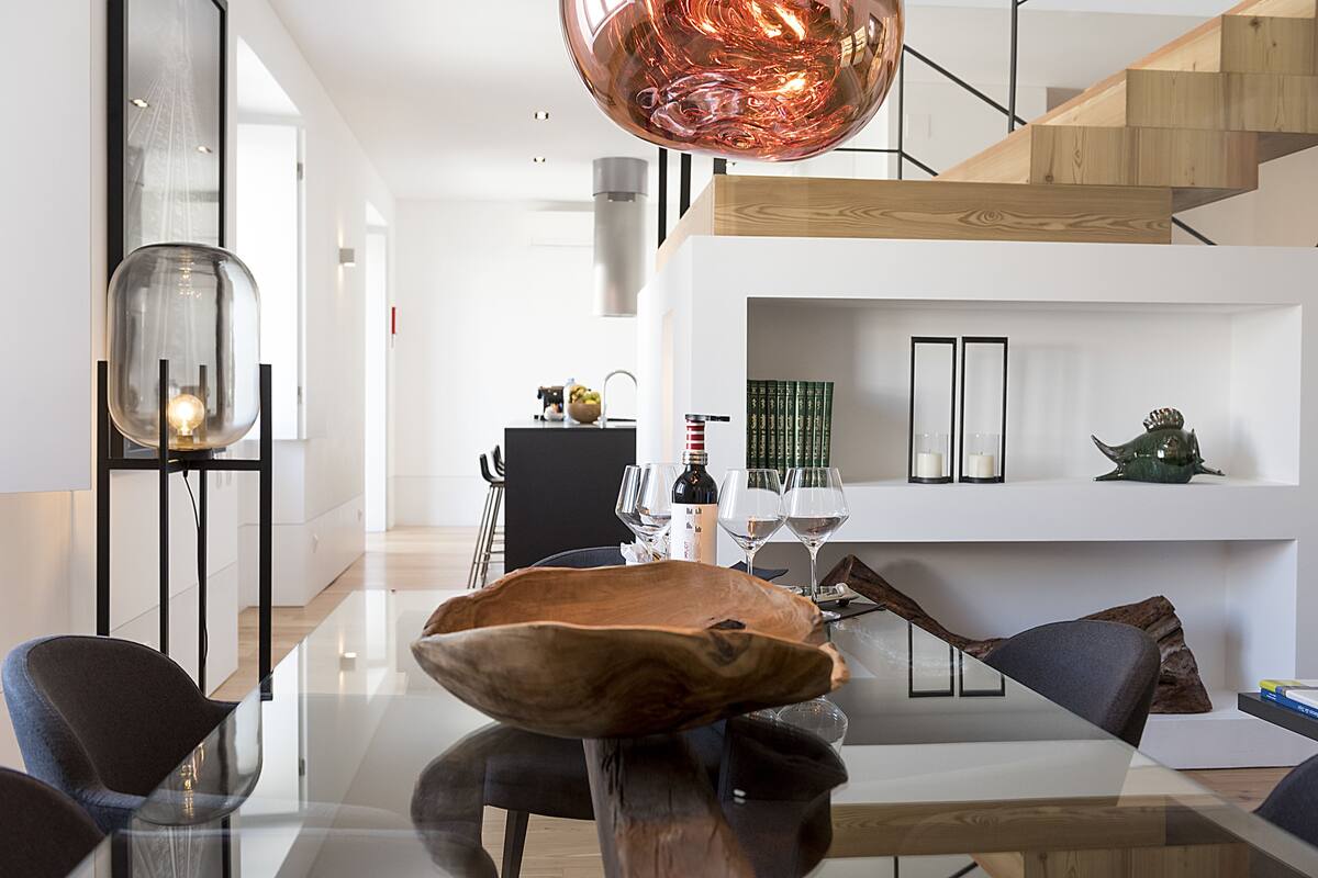 A modern dining area with a glass table, wooden bowl centerpiece, and contemporary chairs.