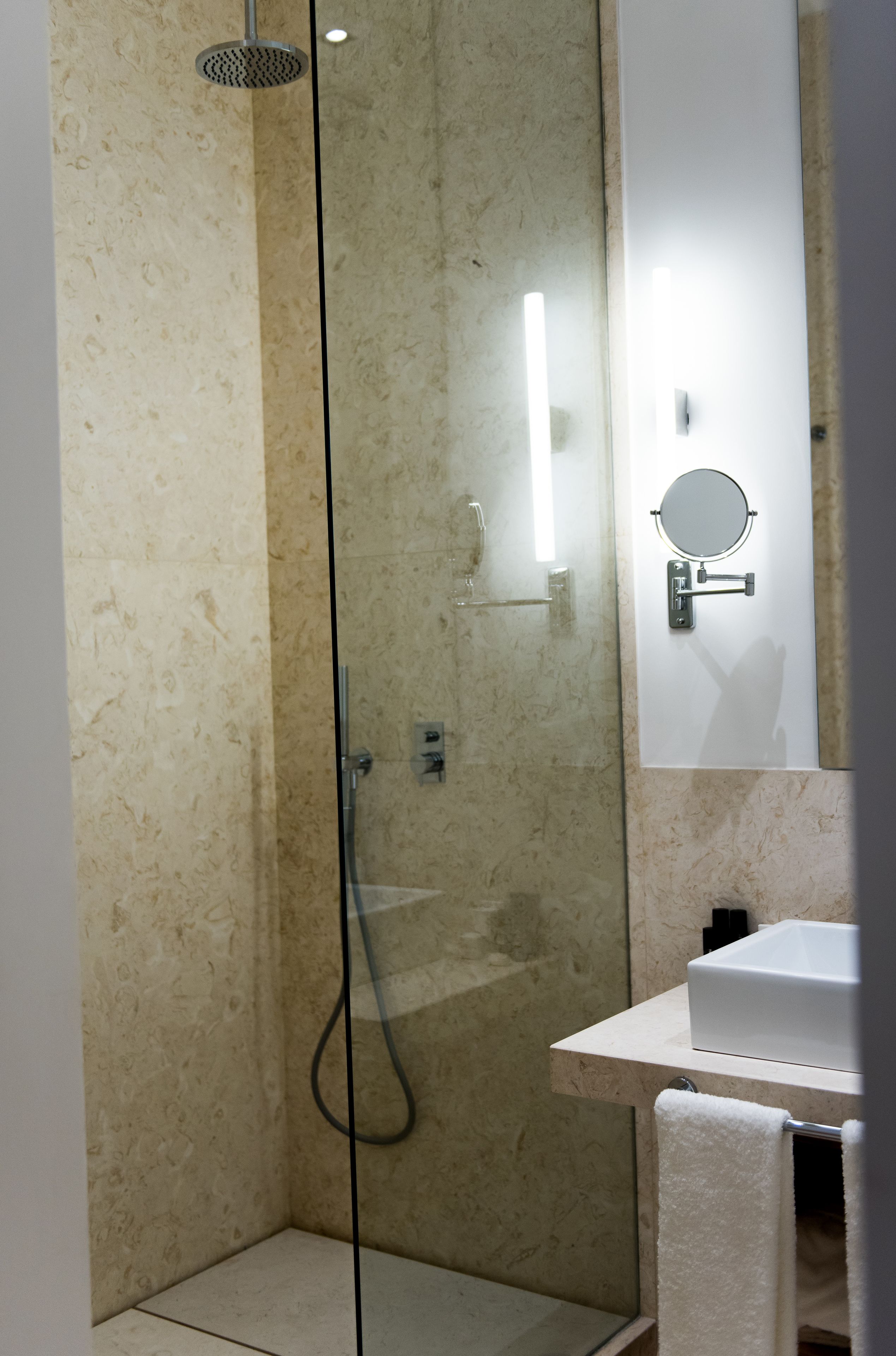 A modern bathroom with a glass-enclosed shower, a white sink, and a mirror with a round frame.