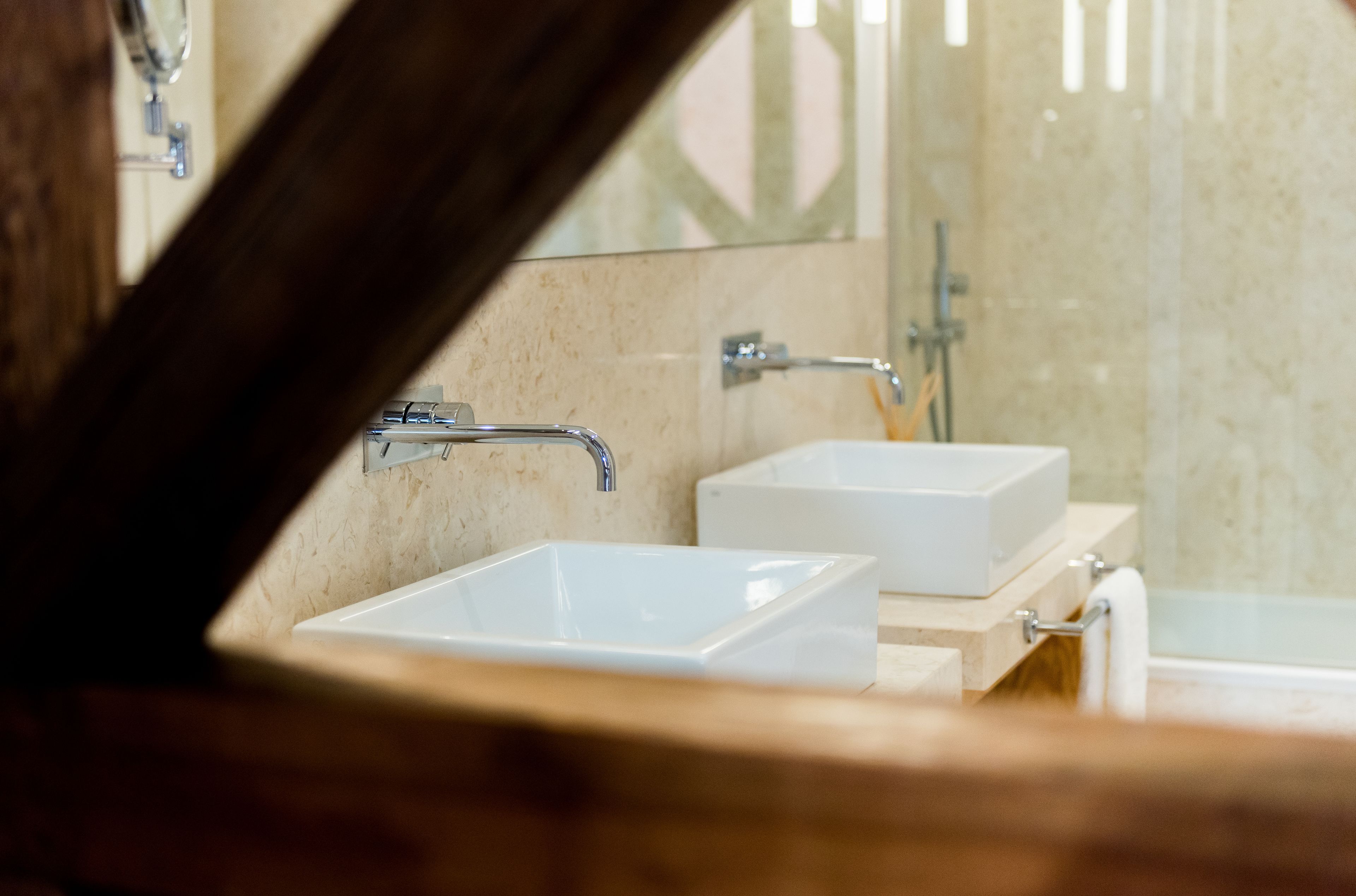 A bathroom with two white sinks, a mirror, and a shower.