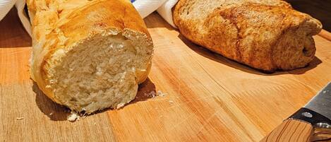 Two loaves of bread on a wooden cutting board with a knife.