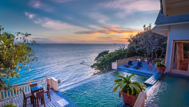A poolside area with a view of the sea and a sunset.