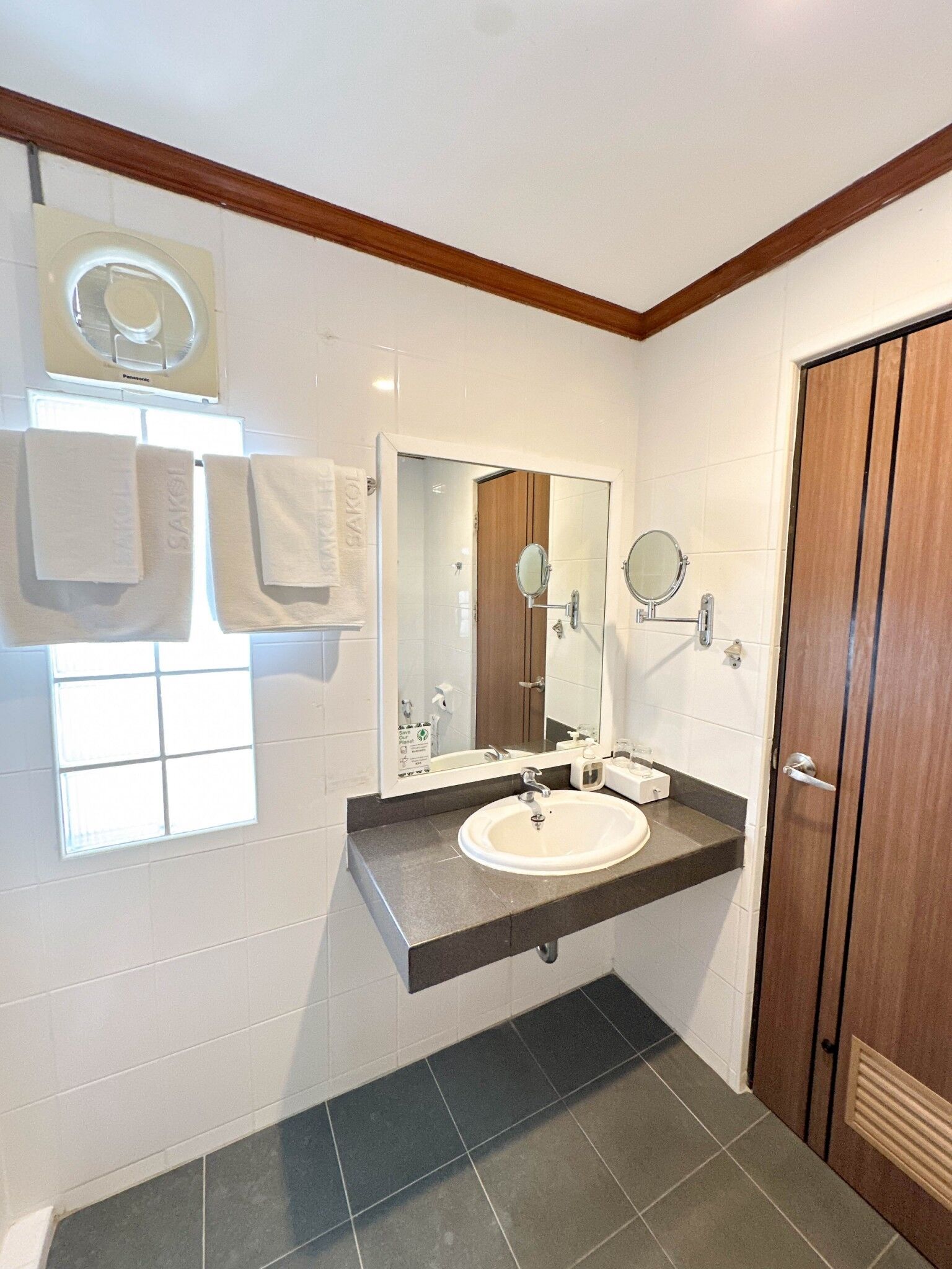 A bathroom with a white sink, a mirror, and a towel rack.