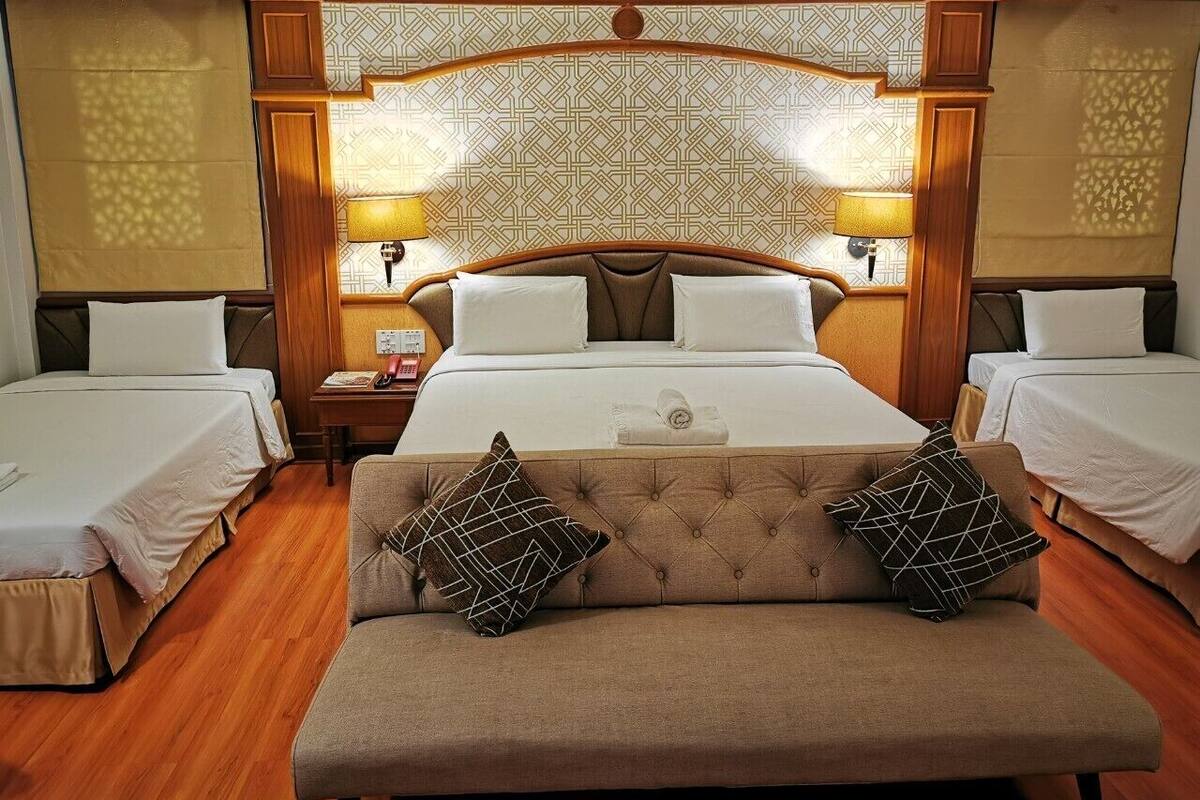 A hotel room with a large bed, two bedside tables, a sofa, and patterned wallpaper.