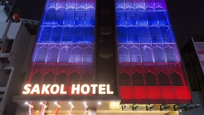 Het uiterlijk van Hotel Sakol, met verlichte borden en een moderne gevel.
