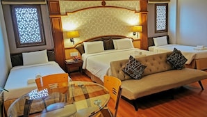 Een hotelkamer met een bed, een slaapbank, een glazen tafel en twee bedlampen.
