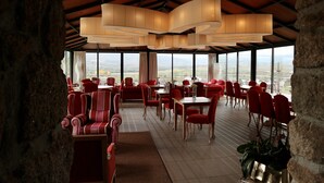 A restaurant with red chairs and tables, large windows, and a view of the landscape. - Quinta da Terrincha (Torre de Moncorvo)