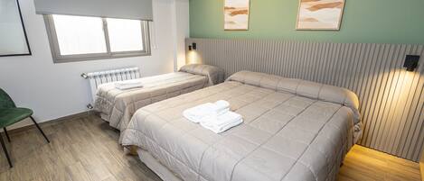 Une chambre d’hôtel avec deux lits, un radiateur, un mur vert et des œuvres d’art.