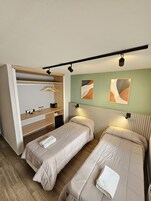 Un dormitorio con dos camas, un armario empotrado y cuadros en la pared.