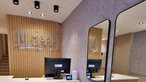 Mostrador de recepción con computadora, teléfono y un pequeño mostrador.