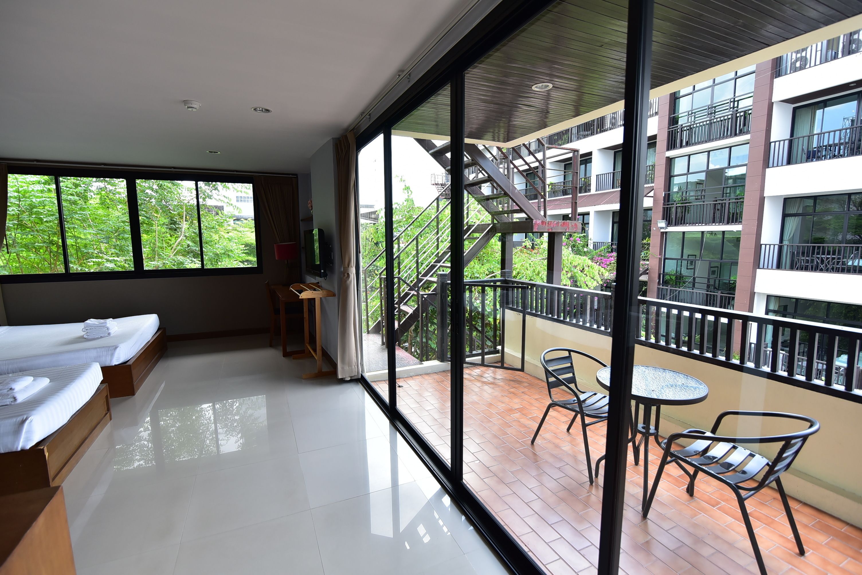 Habitación de hotel moderna con balcón, ventanas amplias y vista al exterior del edificio.