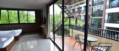 Habitación de hotel moderna con balcón, ventanas amplias y vista al exterior del edificio.