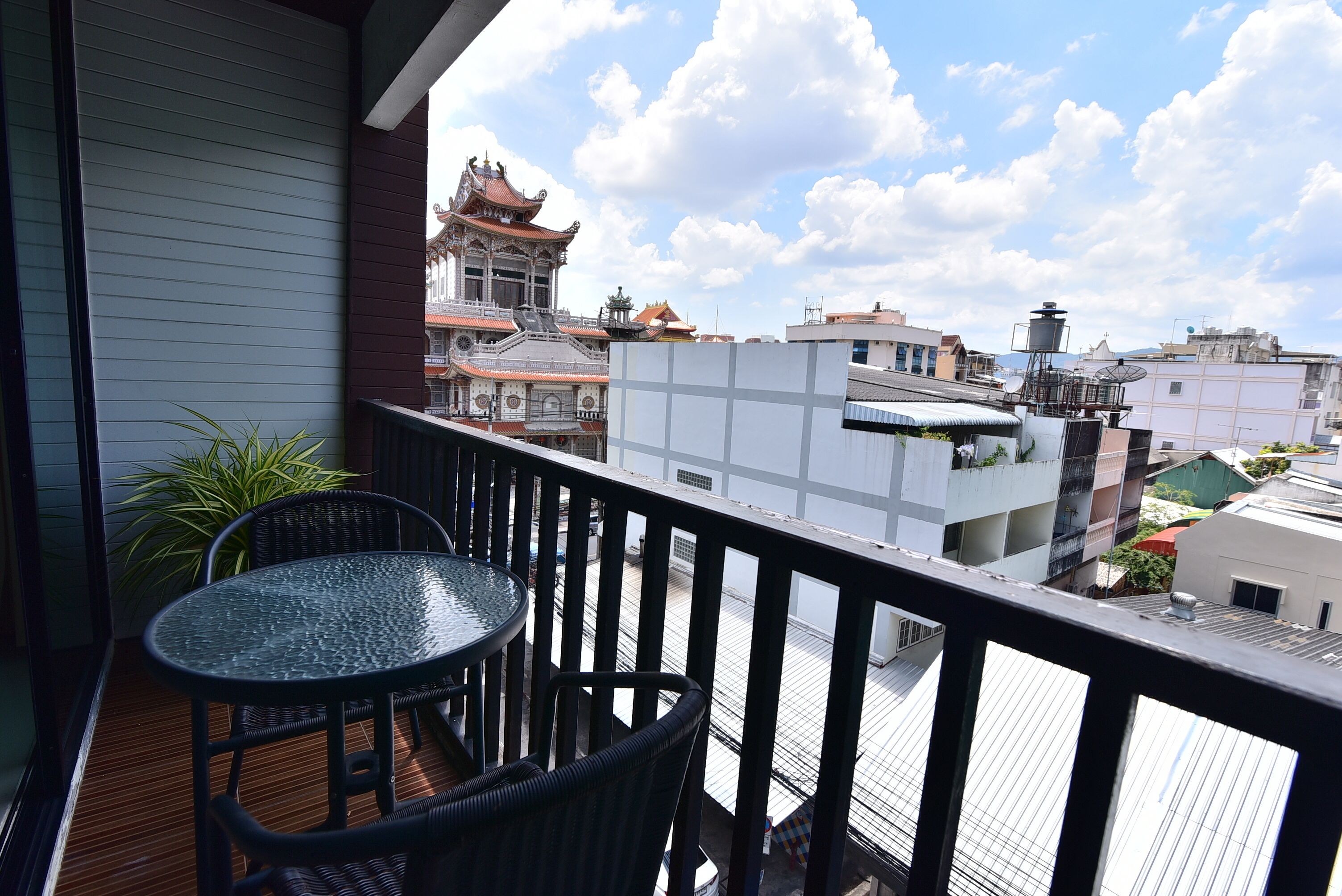 Un balcón con una mesa y sillas, con vista a un edificio tradicional con tejado de baldosas.