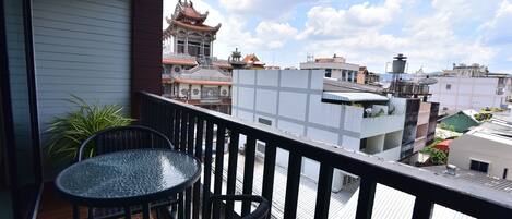 Un balcón con una mesa y sillas, con vista a un edificio tradicional con tejado de baldosas.