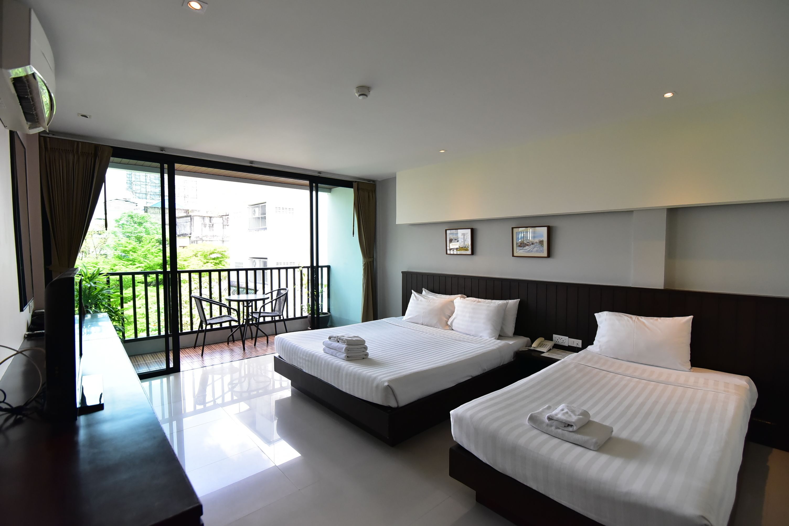 A hotel room with two beds, a balcony, and a desk with a chair.