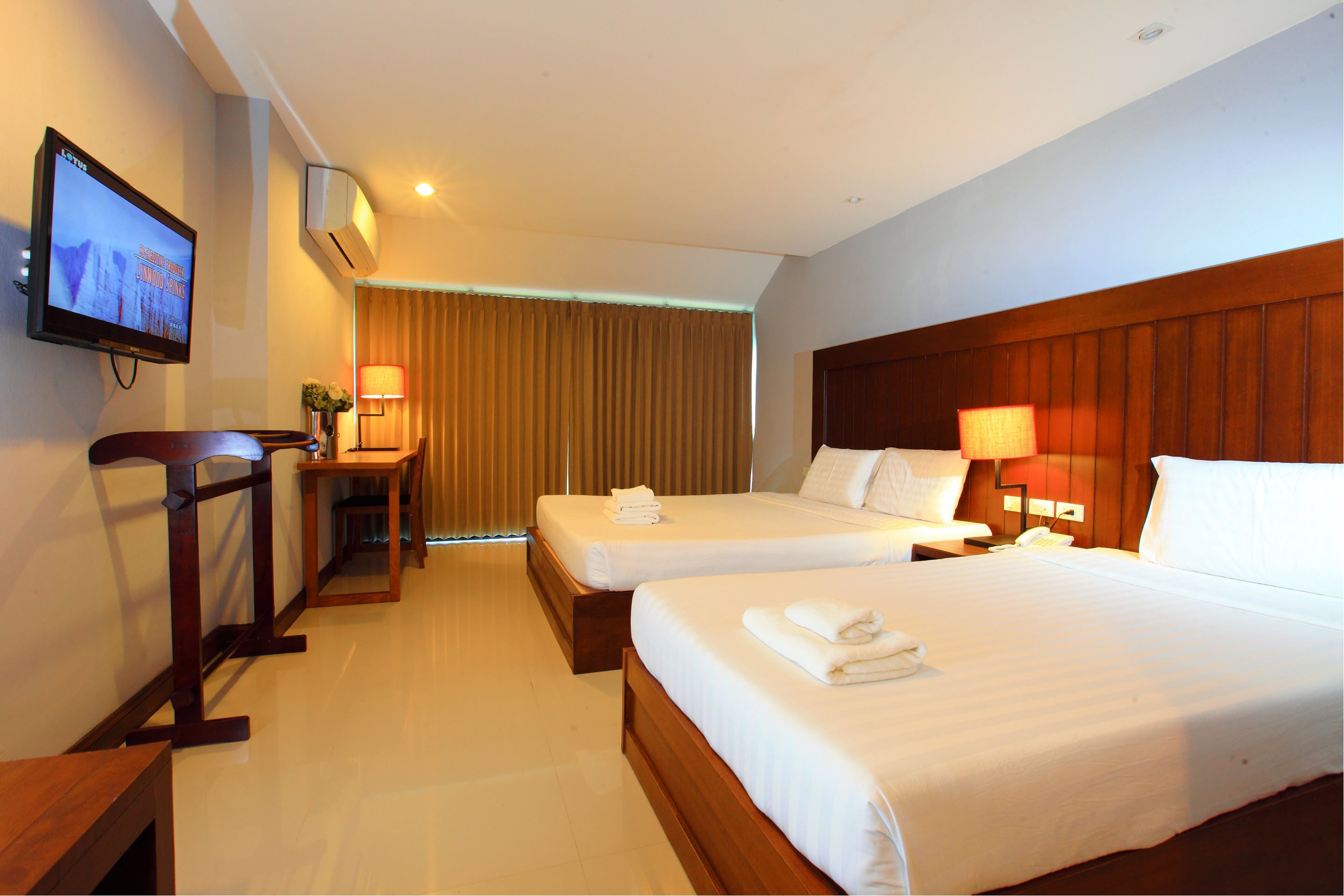 Habitación de hotel con dos camas, televisión, escritorio y lámpara.