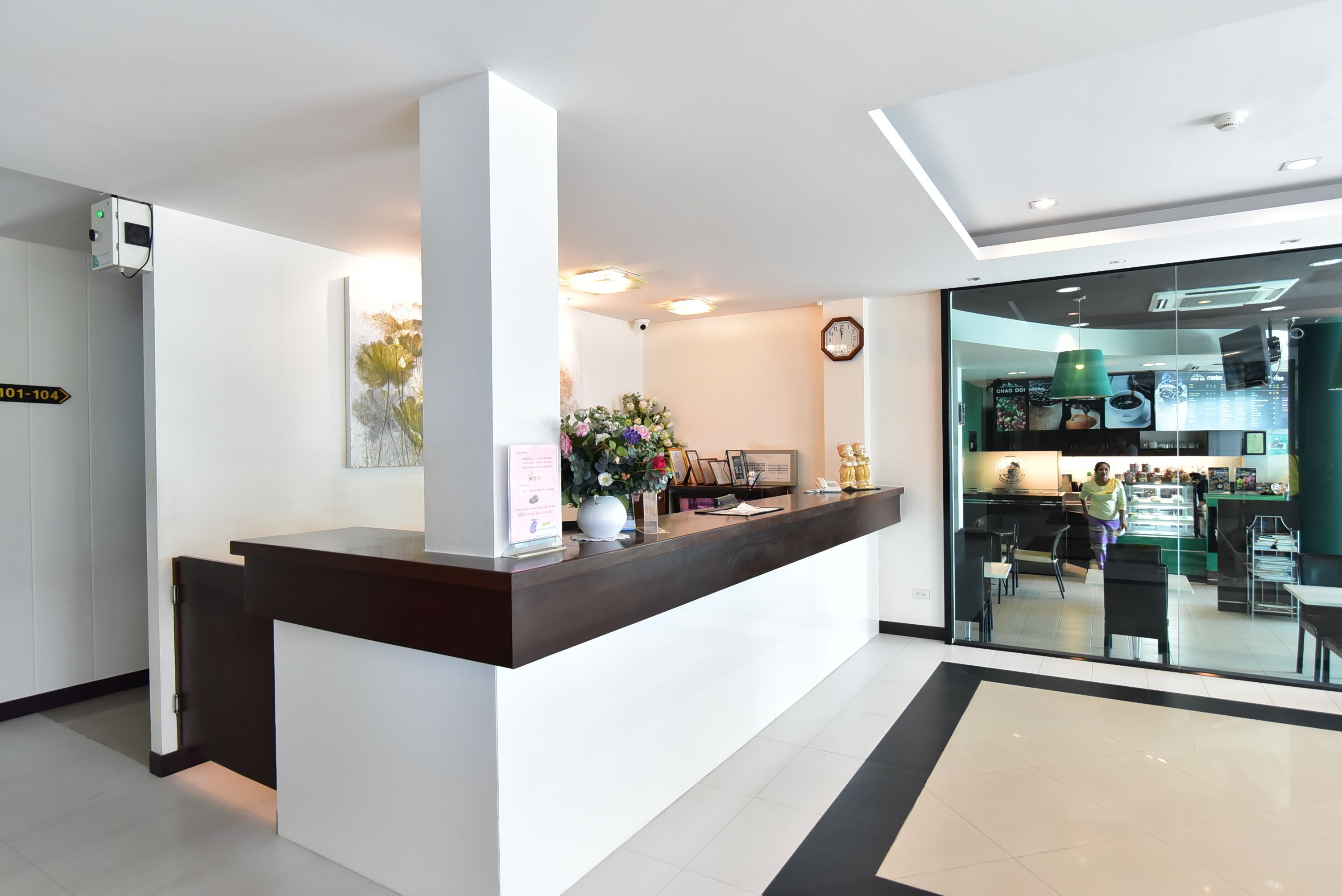 A modern reception desk with a digital screen, a clock, and a vase with flowers.