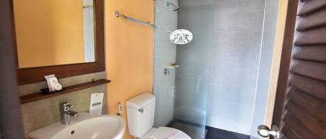 Un baño con lavamanos, inodoro y ducha blancos.