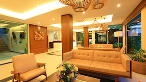 Um lobby moderno com um sofá, cadeiras e um vaso decorativo.