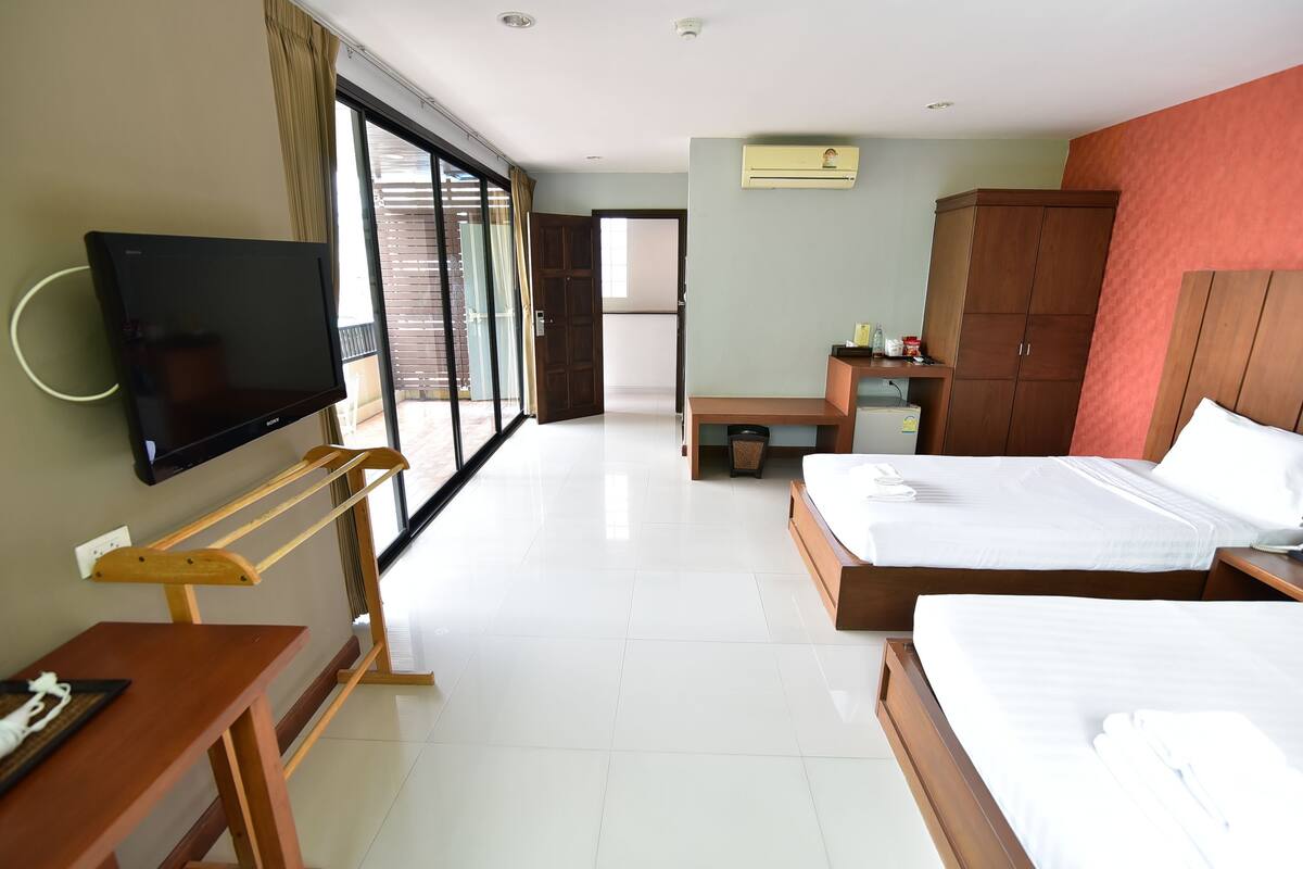 A hotel room with a TV, a desk, a bed, and a wardrobe.