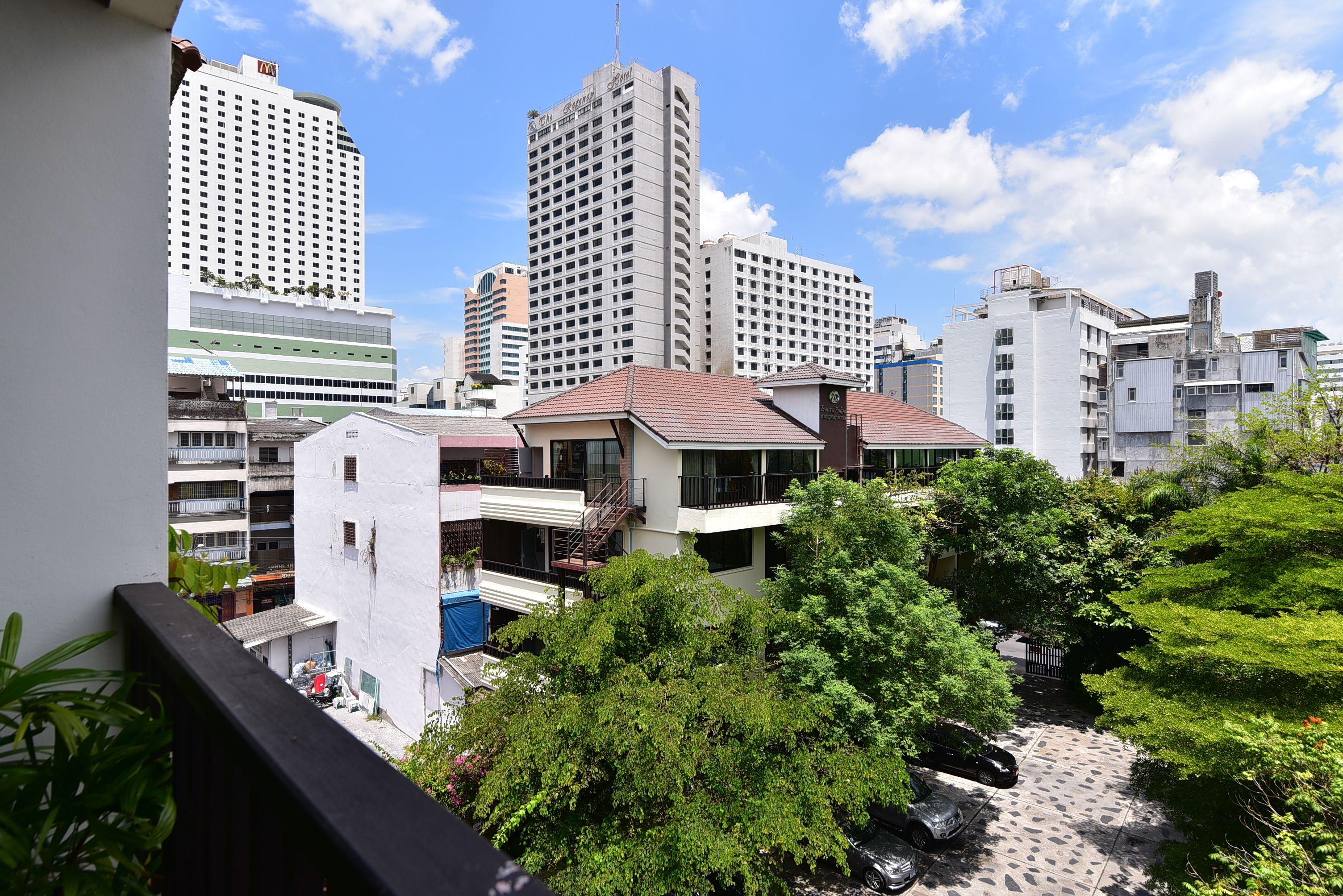A high-rise building with multiple floors, a balcony, and a view of surrounding buildings.