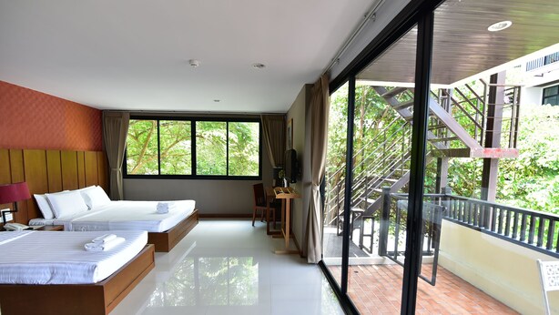 Quarto de hotel moderno com duas camas, varanda e vista para o verde.