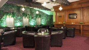 Eine Lounge mit Ledersesseln, einer Bar und einer Wand aus Stein.