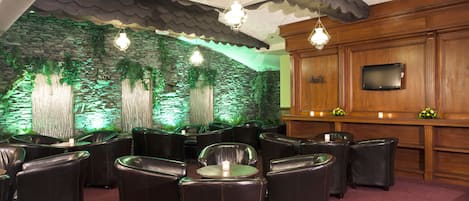 A lounge area with leather chairs, a bar, and a stone wall backdrop.