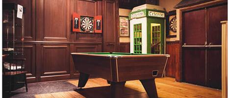 A billiards room with a pool table, dartboards, and a telephone booth.