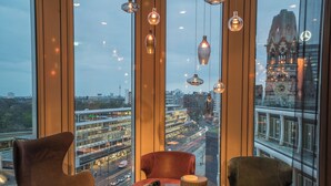 Un interior moderno con amplios ventanales, vistas a la ciudad y muebles contemporáneos.