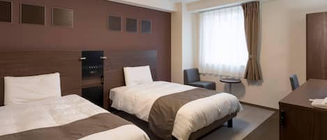 A hotel room with two beds, a desk, a chair, and a window with curtains.