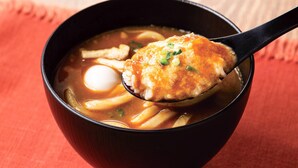 A bowl of ramen with a spoon lifting a piece of meat and a boiled egg. - Comfort Hotel Toyohashi (Toyohashi)