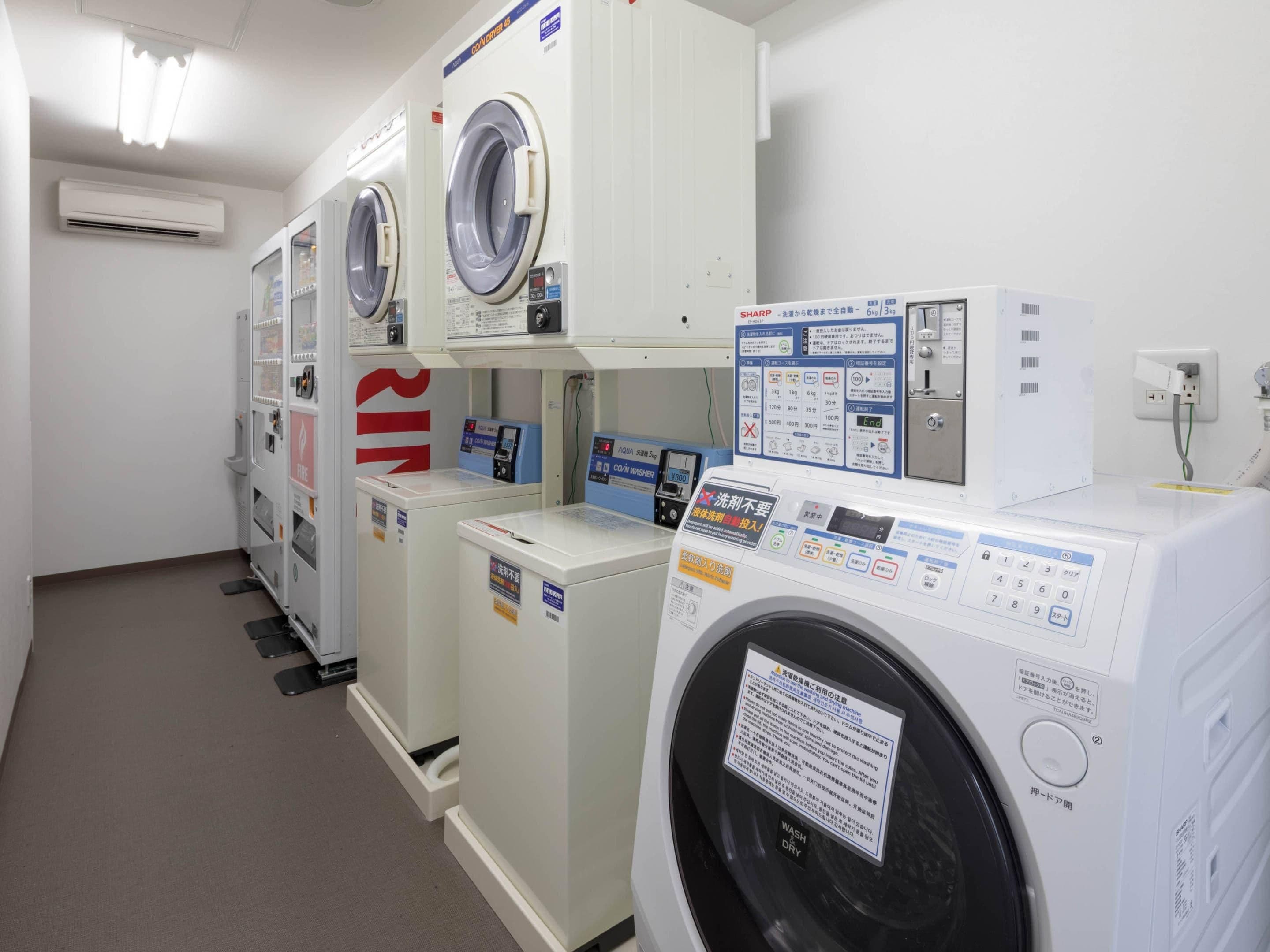 A row of white, modern, front-loading washing machines in a commercial setting.