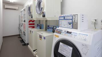 A row of white, modern, front-loading washing machines in a commercial setting.
