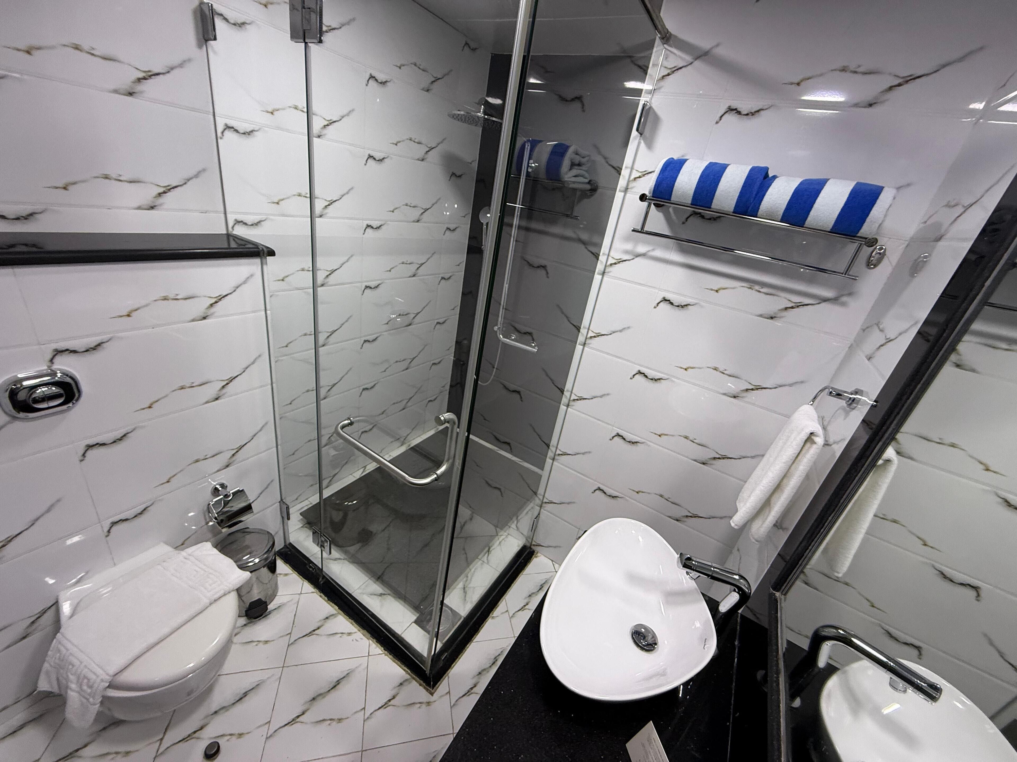 Un bagno moderno con doccia vetrata, lavandino bianco e toilette.