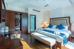 A hotel room with a large bed, a desk, and a wardrobe.
