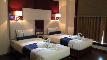 Two double beds with blue and white striped bedspreads and matching pillows, a tufted headboard, and wall-mounted lamps.