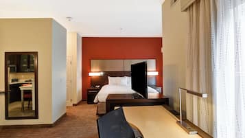 A hotel room with a bed, bedside table, chair, desk, and a mirror.