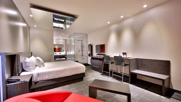 A modern hotel room with a bed, desk, and seating area. - Hôtel Ô Laval (Laval)
