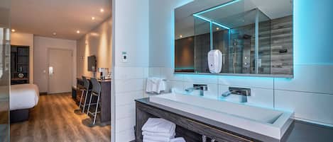Un baño moderno con un espejo grande, lavamanos dobles y una zona de ducha.