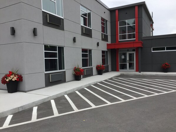 A modern building with a red accent, large windows, and potted plants. - Hôtel Ô Laval (Laval)