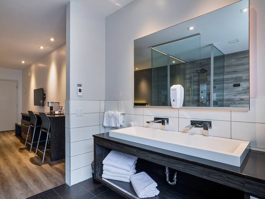 A modern bathroom with a large mirror, a double sink, and a towel rack.