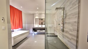 A modern bathroom with a glass-enclosed shower, a large bathtub, and a vanity with a mirror. - Hôtel Ô Laval (Laval)
