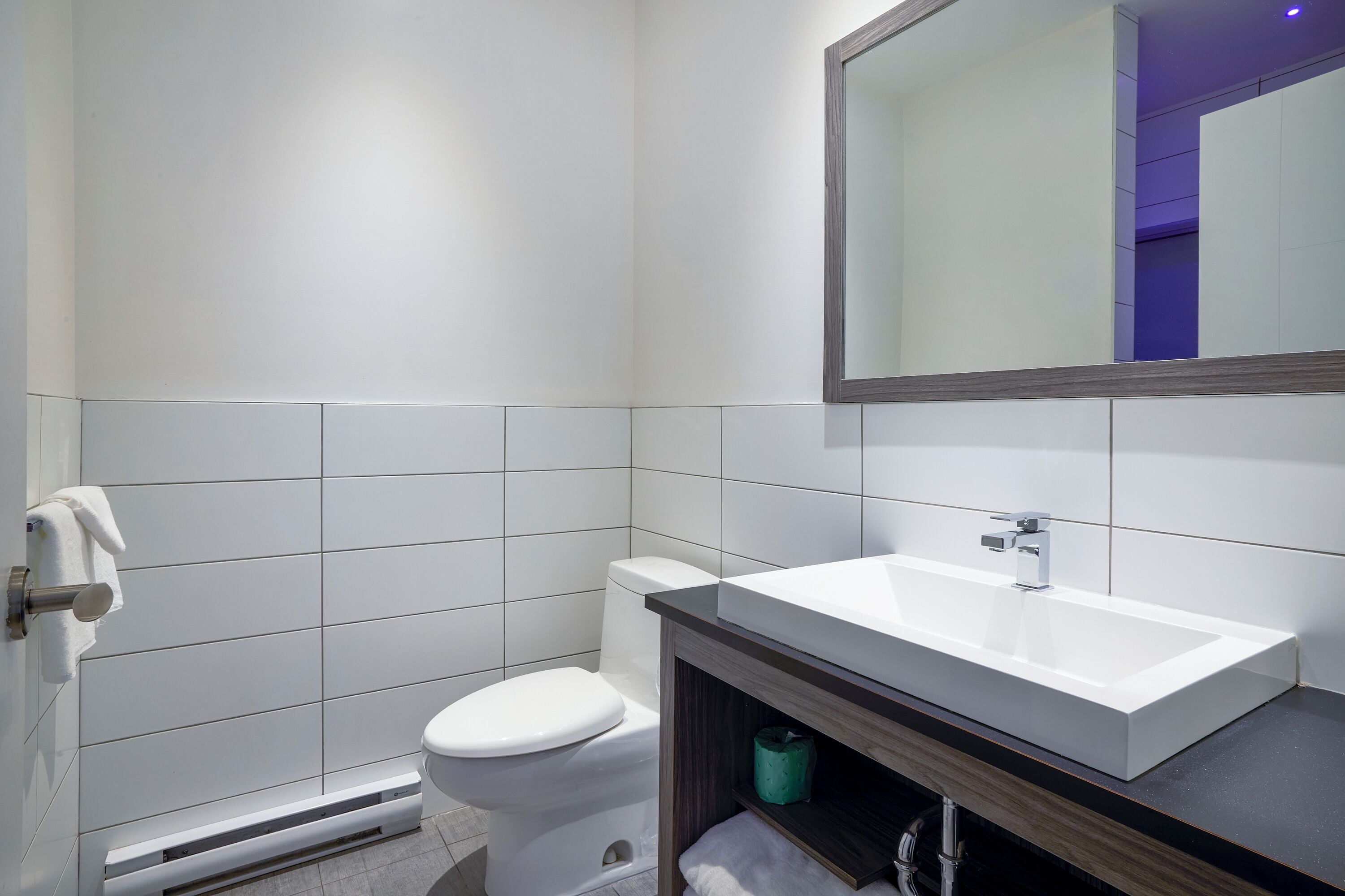 Ein modernes Badezimmer mit Toilette, Waschbecken und einem Spiegel darüber.